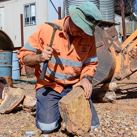 Boulder opal miner splitting ironstone concretion