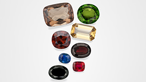 Figure 1. These examples of gem minerals that formed in magmatic environments are part of GIA’s Eduard Gübelin Collection. From top to bottom and left to right: 29.96 ct sanidine feldspar from Germany, 53.00 ct peridot from Myanmar, 11.58 ct zircon from Thailand, 20.66 ct topaz from Utah, 2.05 ct sapphire from Thailand, 18.36 ct pyrope garnet from the Czech Republic, 19.55 ct black spinel from Thailand, and 2.50 ct ruby from Thailand. Photos by Robert Weldon.