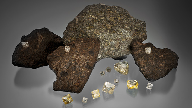 Figure 9. Diamond crystals (1.24–22.32 ct) and samples of diamond-bearing kimberlite. Photo by Orasa Weldon. The loose crystals were donated to GIA by De Beers as part of the Sir Ernest Oppenheimer Student Collection.