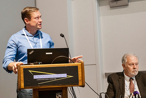 Figure 2. Aaron Palke presented the various types of melt inclusions in Montana’s secondary sapphire. James Shigley (seated) moderated the session. Photo by Robert Weldon.
