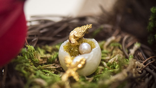 Figure 11. In this “Mother’s Love” pendant, a large pearl was carved to resemble a bird’s nest and decorated with small gemstone druzy, a round pearl, and a bird made of gold. Photo by Kevin Schumacher.