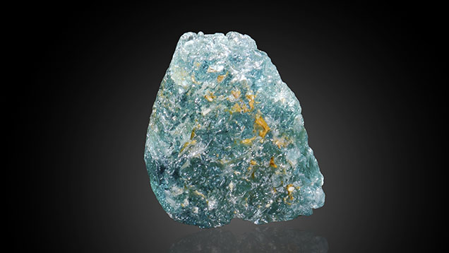Figure 1. This deeply etched 11.24 mm laurentthomasite crystal from Madagascar displayed a rich greenish blue color. The orange color patches are epigenetic limonitic residue. Photo by Annie Haynes; courtesy of Arkfeld Minerals.