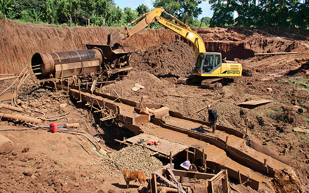 Figure 12. Mining of eluvial gem-bearing sediments from very weathered lava flows with mechanical equipment including a mechanical excavator, a rotating trammel cage to separate large rock pieces from the sediments, and a long sluice box to wash the sediments. This photo was taken in November 2020 at Khao Ploy Waen, an eroded volcano where sapphire is mined near Chanthaburi in eastern Thailand. Photo by Wim Vertriest.