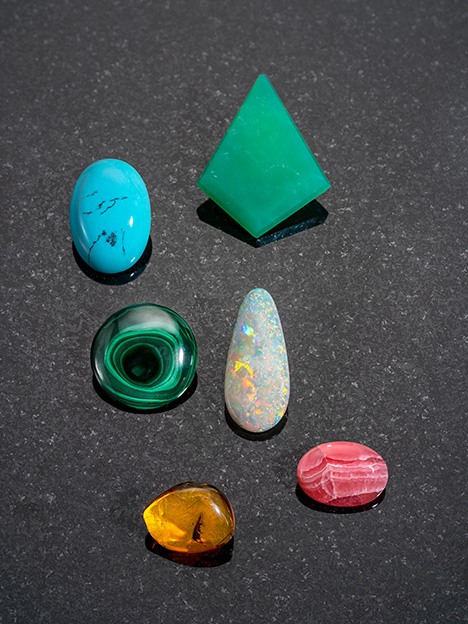Figure 2. The gems shown here formed in sediments by the evaporation of water or from mineralized solutions (amber is solidified tree resin). From left to right and top to bottom: 59.88 ct turquoise, Turkey; 75.30 ct chrysoprase, Queensland, Australia; 67.79 ct malachite, Democratic Republic of Congo; 19.56 ct opal, Brazil; 14.67 ct amber, Poland; and 28.14 ct rhodochrosite, Argentina. Composite image by Robert Weldon.