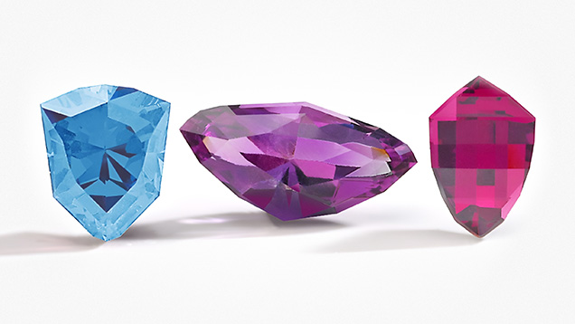 Figure 2. Gemstone cutters in Kenya, Malawi, and Zambia developed cuts to represent their countries in Virtu Gem&rsquo;s National Gem Cut Course. Left to right: the Kenya Cheetah Head, Zambia Eagle, and Malawi <em>Mbuna</em> Fish cuts in aquamarine, amethyst, and rhodolite garnet. Photo courtesy of Virtu Gem.