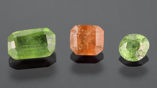 Figure 1. Demantoid garnet (0.84 ct on the left and 0.28 ct on the right) and an orange grossular garnet (0.55 ct) from Sonora, Mexico. Photo by Diego Sanchez.