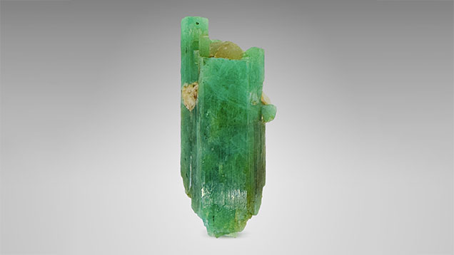 Figure 6. The largest known emerald crystal from Zhen’an to date, weighing 34.34 g and measuring 6.3 cm long, with associated quartz and albite. Photo by Xiao-Yan Yu.