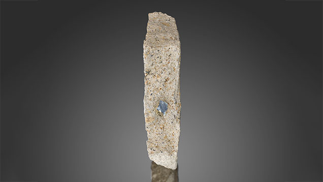 Figure 21. This 6 mm long sapphire in French Bar sill basaltic trachyandesite (RK-FBS 061) displays a small amount of easily visible biotite (phlogopite). Photo by Jeff Mason.