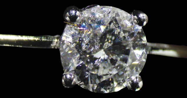 Figure 1. A round brilliant-cut diamond set in the necklace exhibits the flash effect (indicated by arrow) when tilted, a characteristic of fracture filling caused by the presence of a filler within a surface-reaching fracture. Photo by Gaurav Bera.