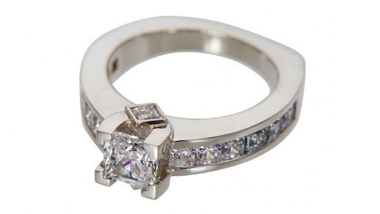 这枚戒指拥有一颗大的公主式切工精度切割的主石、十二颗槽镶小宝石，以及两个公主式切工包镶宝石。 您将通过精美的珠宝作品增强技艺。