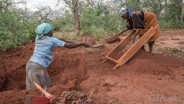 Two woman digging and sifting soli as they dig for gems. 