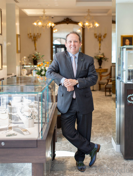 Standing man in a suit leans on a jewelry counter.