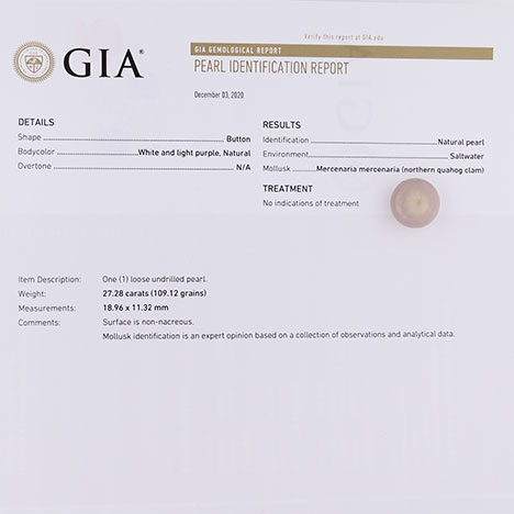 A quahog pearl sitting on a printed GIA Pearl Identification Report.