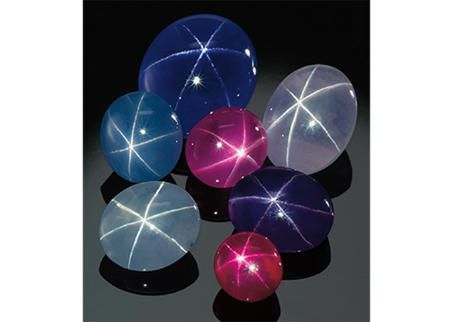 A group of star sapphires, fancy star sapphires and one star ruby on a black background 